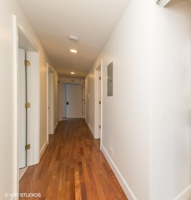 hallway featuring electric panel, recessed lighting, baseboards, and wood finished floors