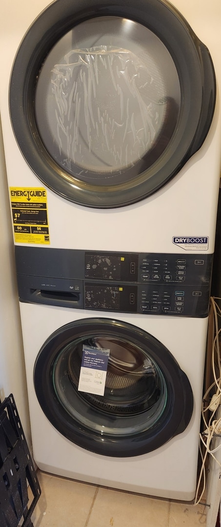 laundry room with stacked washer and clothes dryer, laundry area, and tile patterned flooring