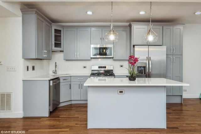 kitchen with a center island, a sink, visible vents, gray cabinetry, and appliances with stainless steel finishes