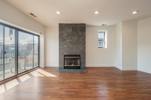 unfurnished living room featuring baseboards, visible vents, wood finished floors, and a fireplace