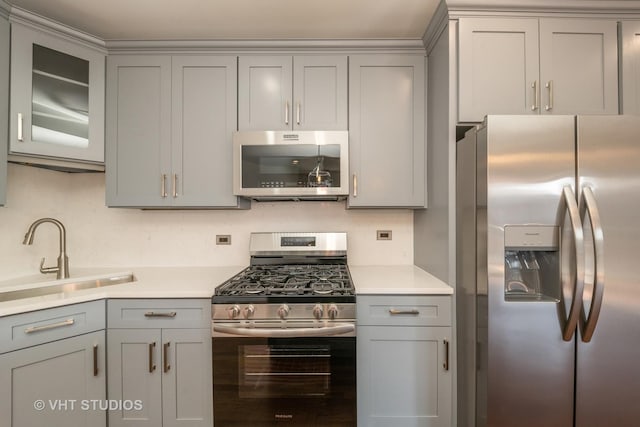 kitchen with light countertops, gray cabinets, stainless steel appliances, and a sink