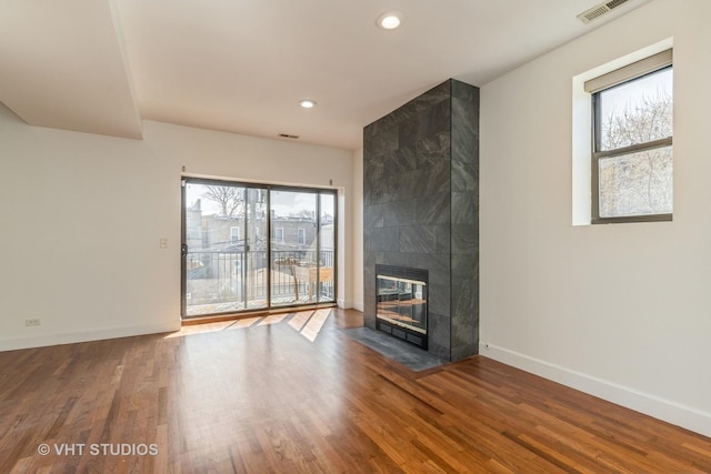unfurnished living room featuring baseboards, a fireplace, visible vents, and wood finished floors