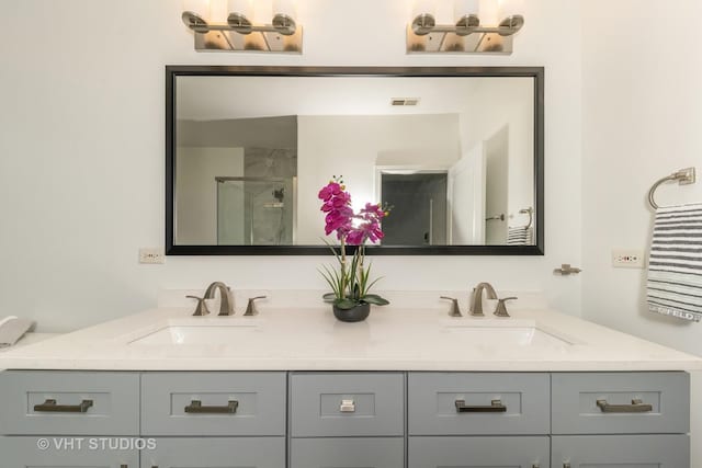 bathroom with a shower stall, double vanity, and a sink
