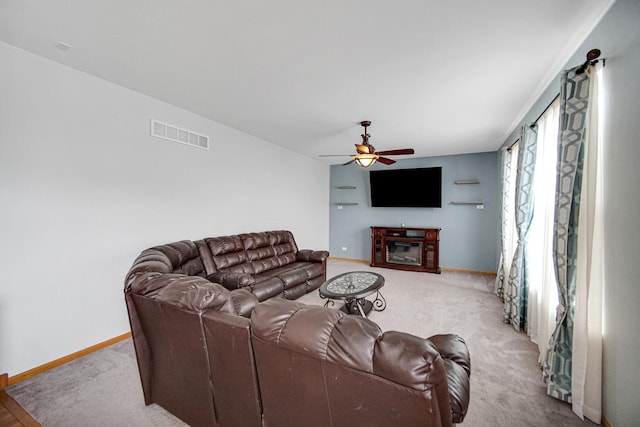 carpeted living room with a ceiling fan, baseboards, and a glass covered fireplace