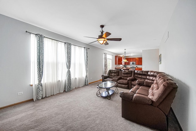 living room featuring a ceiling fan, baseboards, and light carpet