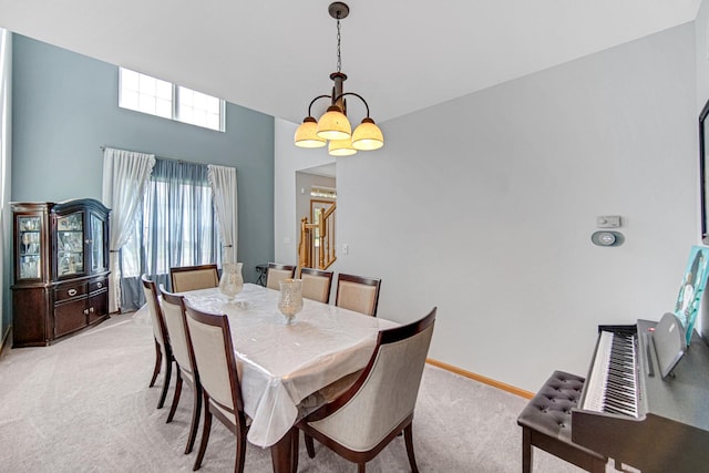 dining area featuring light carpet, a towering ceiling, and baseboards