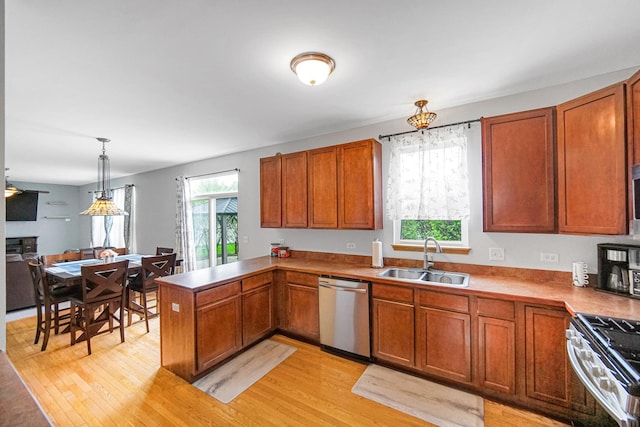 kitchen with a sink, appliances with stainless steel finishes, light wood-type flooring, and a peninsula