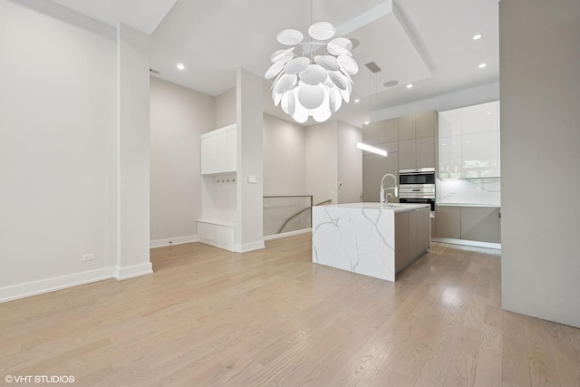 216 S Green St Unit 1N, Chicago, IL 60607 - kitchen with modern cabinets, a chandelier, light wood finished floors, an island with sink, and light countertops