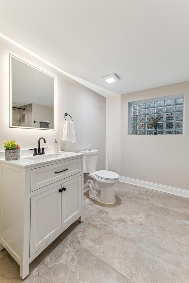 bathroom featuring vanity, toilet, and baseboards