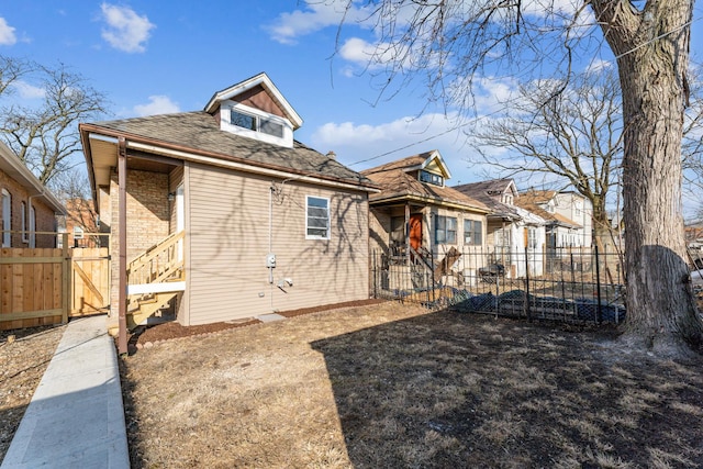 exterior space featuring a shingled roof, a gate, and fence
