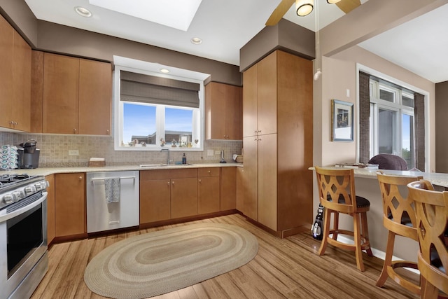 390 S Western Ave Unit 703, Des Plaines, IL 60016 - kitchen featuring light wood finished floors, a sink, a skylight, backsplash, and appliances with stainless steel finishes