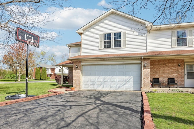 view of front facade with driveway, a garage, brick siding, and a front yard