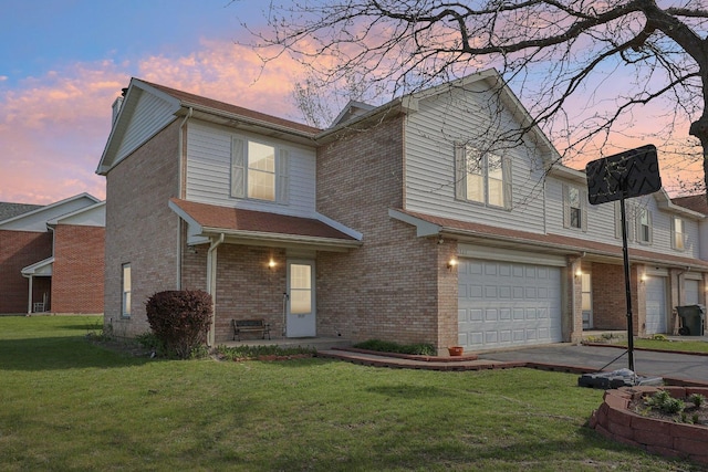 view of front of property with an attached garage, a yard, brick siding, and driveway