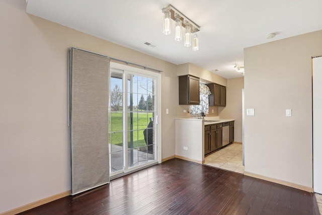 unfurnished living room featuring a sink, light wood-type flooring, and baseboards