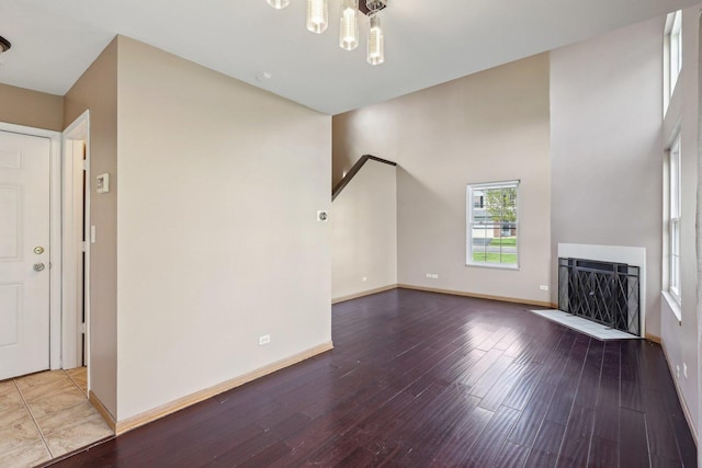 unfurnished living room featuring wood finished floors, a fireplace with flush hearth, baseboards, and a chandelier