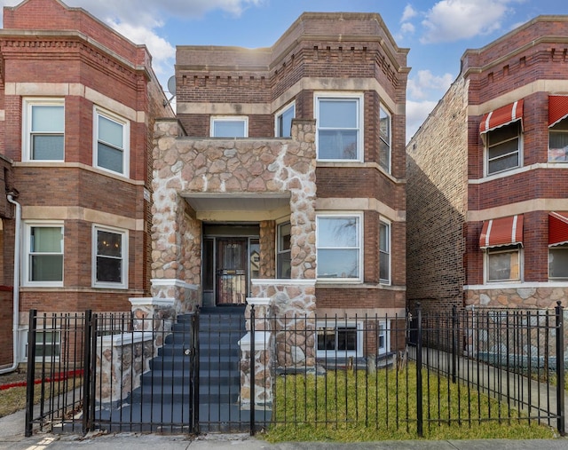 4843 W Gladys Ave, Chicago, IL 60644 - multi unit property featuring a fenced front yard, stone siding, a gate, and brick siding