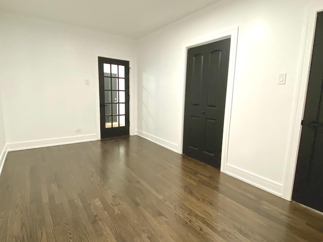 spare room featuring baseboards and dark wood finished floors