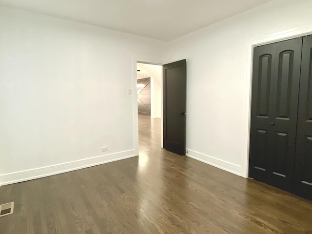 unfurnished bedroom with baseboards, a closet, visible vents, and dark wood-style floors