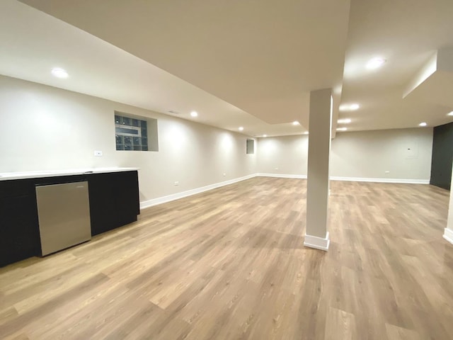 finished basement featuring baseboards, indoor bar, light wood finished floors, and recessed lighting