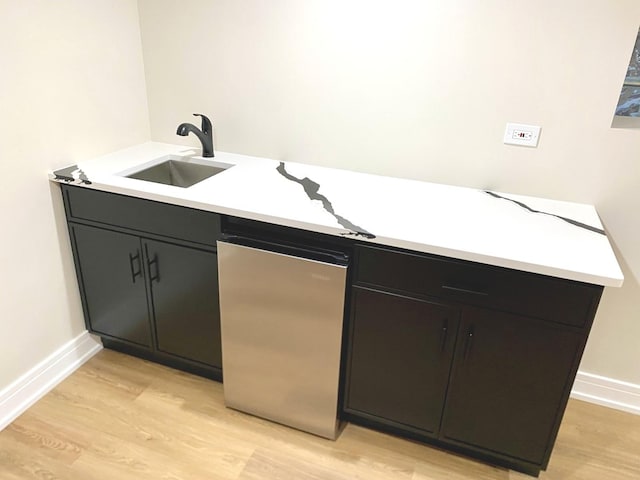 interior space with light wood-type flooring, baseboards, and a sink