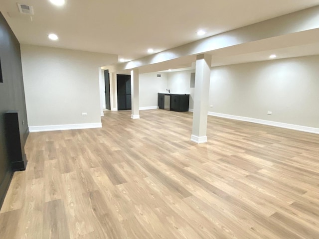 finished basement featuring visible vents, light wood-style flooring, baseboards, and recessed lighting