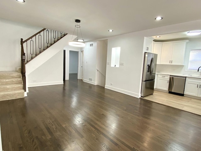 unfurnished living room featuring baseboards, stairway, recessed lighting, and wood finished floors