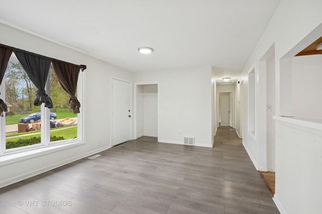 spare room with baseboards, visible vents, and wood finished floors