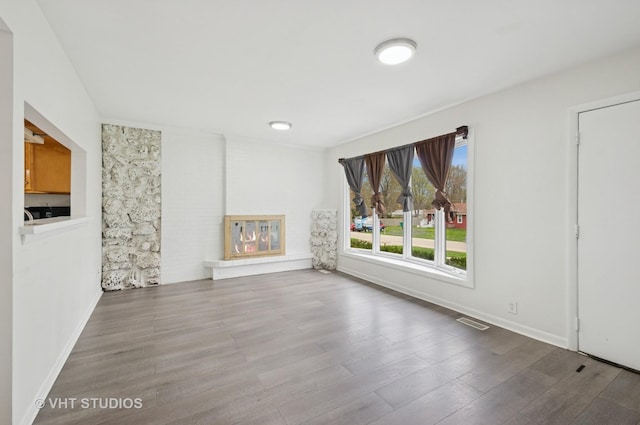 unfurnished room featuring baseboards, visible vents, and wood finished floors