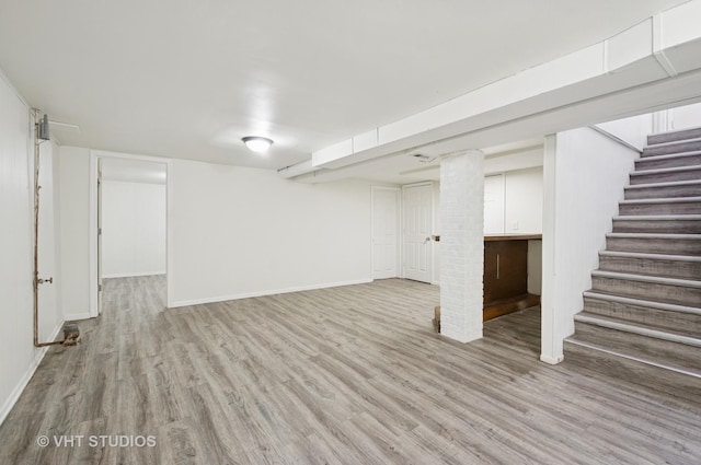 finished below grade area with baseboards, stairway, and wood finished floors