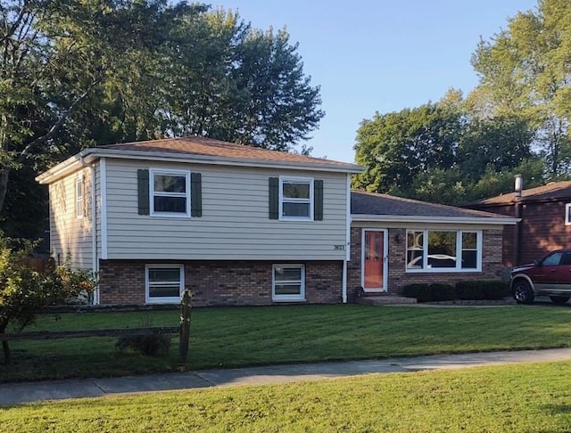 split level home with a front yard and brick siding