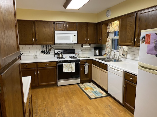 kitchen featuring light countertops, tasteful backsplash, a sink, and white appliances