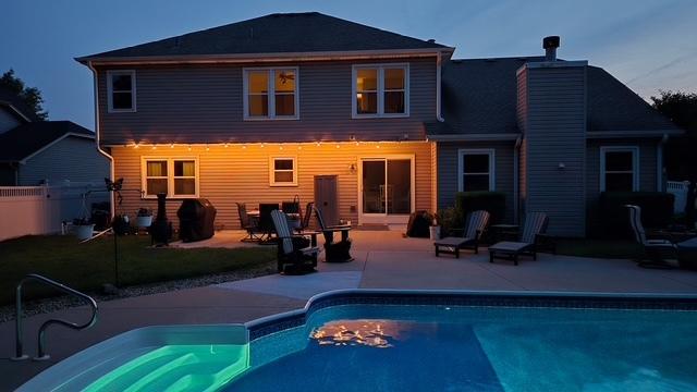 2020 Saint Andrews Dr, Plainfield, IL 60586 - back of house at dusk with a patio, a chimney, and an outdoor pool