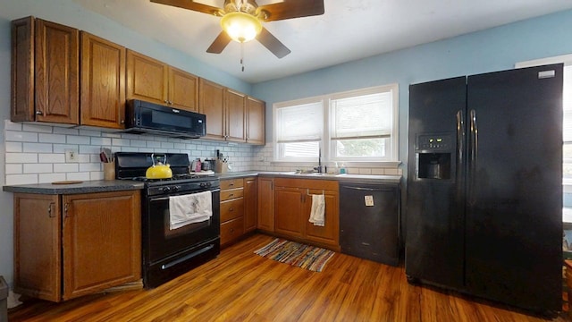 1013 W Springfield Ave, Champaign, IL 61821 - kitchen with black appliances, wood finished floors, a sink, and brown cabinetry