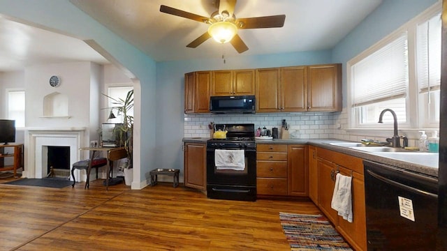 1013 W Springfield Ave, Champaign, IL 61821 - kitchen featuring black appliances, a sink, backsplash, dark wood-style floors, and a fireplace with flush hearth