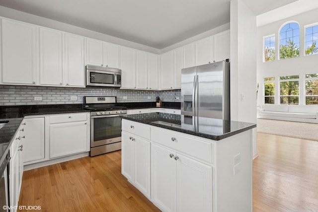 62 Andover Cir, Northbrook, IL 60062 - kitchen featuring appliances with stainless steel finishes, light wood-type flooring, tasteful backsplash, white cabinets, and dark stone counters