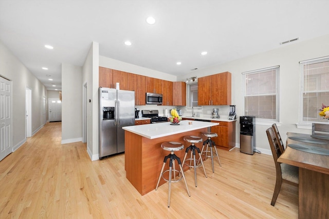 2158 N Natchez Ave Unit 1N, Chicago, IL 60707 - kitchen featuring a kitchen bar, brown cabinetry, visible vents, appliances with stainless steel finishes, and a kitchen island
