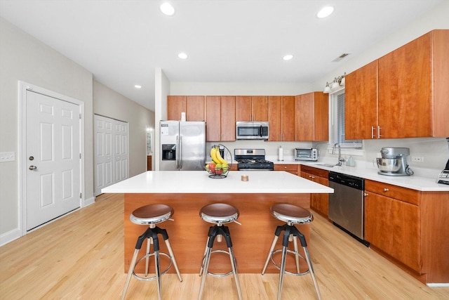 2158 N Natchez Ave Unit 1N, Chicago, IL 60707 - kitchen featuring a center island, a breakfast bar, brown cabinetry, light wood-style floors, and appliances with stainless steel finishes