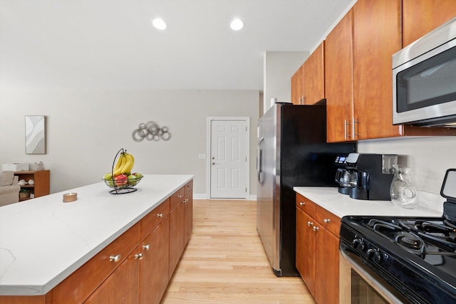 2158 N Natchez Ave Unit 1N, Chicago, IL 60707 - kitchen featuring light stone counters, stainless steel appliances, light wood-style flooring, and brown cabinets
