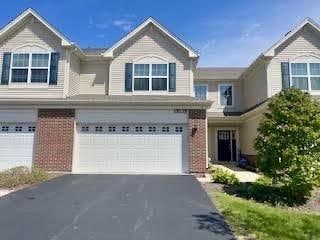 townhome / multi-family property with a garage, brick siding, and driveway