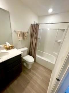 full bathroom featuring toilet, shower / tub combo, wood finished floors, and vanity