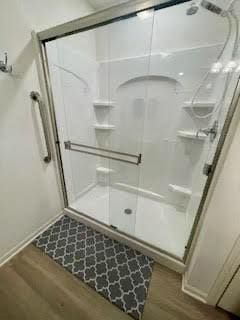 full bath featuring a shower stall and wood finished floors