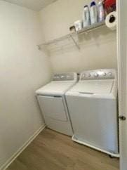 washroom with laundry area, wood finished floors, baseboards, and washer and dryer
