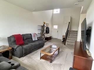 carpeted living area featuring stairway