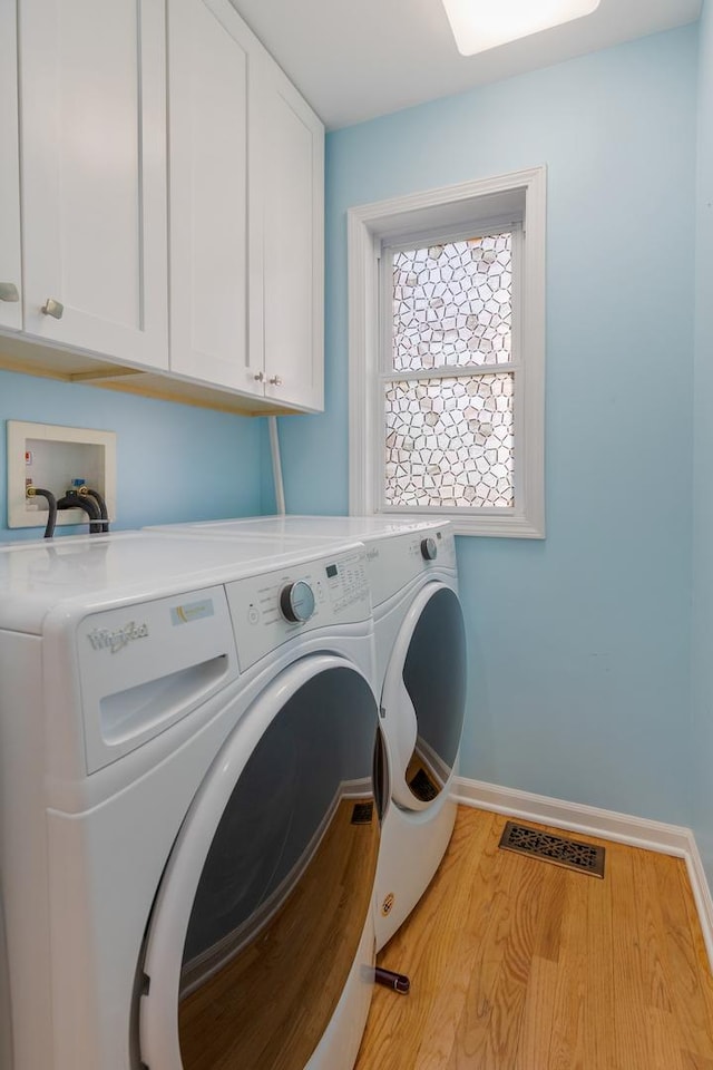 laundry room featuring cabinet space, washer and clothes dryer, baseboards, and wood finished floors