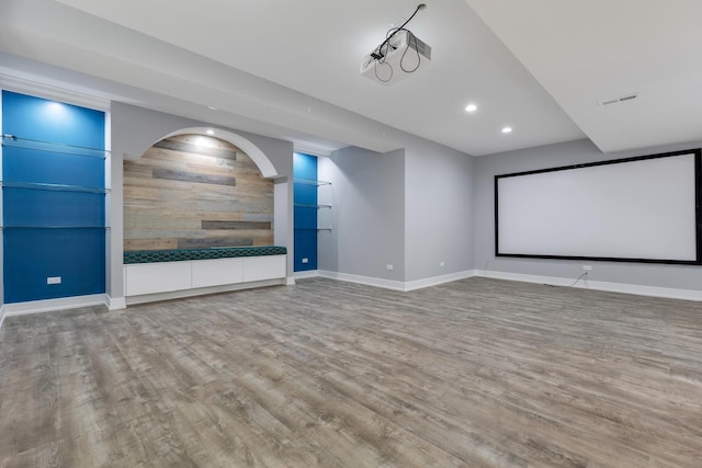 cinema with wood finished floors, recessed lighting, baseboards, wood walls, and arched walkways