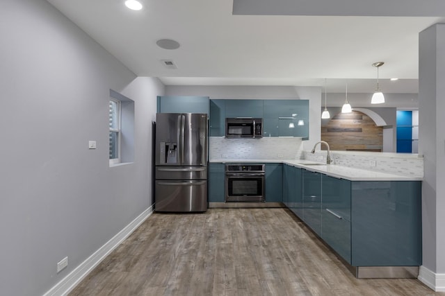 kitchen with appliances with stainless steel finishes, modern cabinets, a sink, decorative backsplash, and wood finished floors