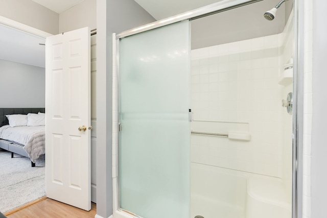 bathroom with wood finished floors, a shower stall, and ensuite bathroom