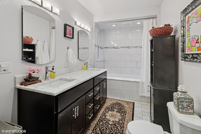 full bath with a sink, double vanity, toilet, and tiled shower / bath combo