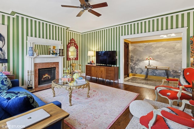 living room featuring a ceiling fan, wood-type flooring, wallpapered walls, baseboards, and a high end fireplace