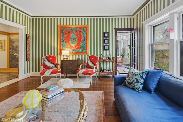 living room with wallpapered walls, wood finished floors, baseboards, and ornamental molding